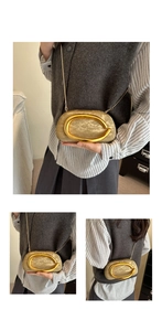 Detail of evening bag with large gold metal ring handle and textured gold fabric surface