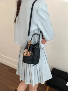 Side view of black lychee grain bucket bag with unique wooden horse charm on a model