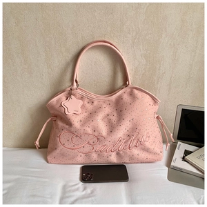 Détail du sac seau rose étoilé avec broderie Badblue et cordons de serrage latéraux