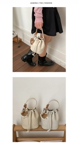 Detail of cream drawstring bucket bag with litchi grain leather and horse charm