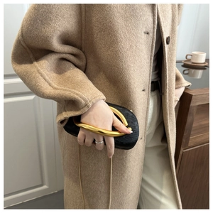 Detail of elegant black evening clutch with luxury gold U-shaped metal handle and chain