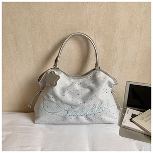 Détail du sac seau argenté à motifs d'étoiles avec broderie Badblue et poignée métal