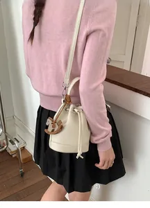 Detail of cream bucket bag with lychee pattern leather and wooden horse charm