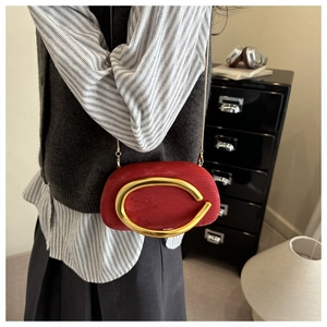 Detail of red small crossbody evening bag with large gold ring buckle worn by model