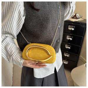 Detail of ginger velvet evening bag with curved metal handle and elegant chain strap