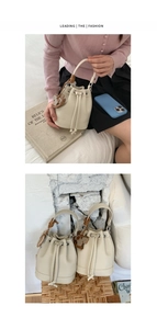 Close-up of beige lychee texture bucket bag with drawstring and horse charm accessory