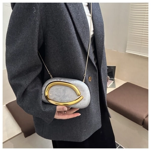 Detail of silver textured evening clutch bag with golden metal arc and chain strap