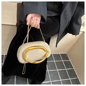 Detailed shot of beige evening clutch with gold ring handle and metal chain strap