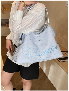 Détail du sac seau bleu clair avec étoiles argentées, broderie Badblue et anses argent