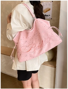 Vue détaillée du sac cabas rose avec motifs d'étoiles argentées et logo embossé sur le côté