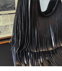 Detailed macro view of layered long tassels on a black matte leather shoulder bucket bag
