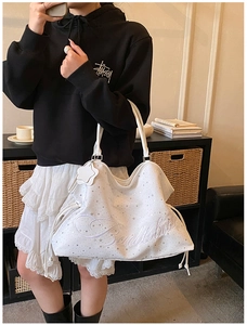 Détail du sac cabas blanc avec étoiles argentées, broderie Badblood et cordon de serrage