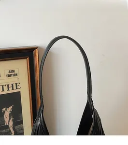 Detail of slim black leather shoulder strap with neat stitching on bucket bag