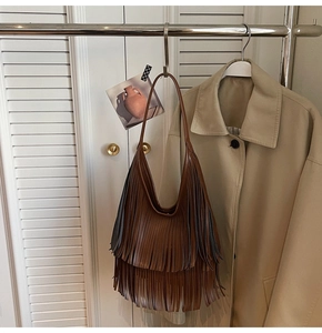 Detail shot of brown hobo bucket bag with long tassels hanging on a metal rack