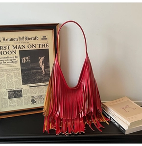 Detail of red hobo bucket bag with long fringe tassels and integrated shoulder strap