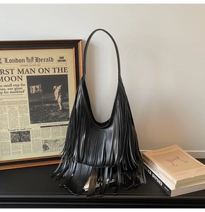 Close-up of black fringe shoulder bag with soft leather texture and long tassels