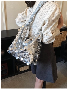 Close-up of silver sequin shoulder bag featuring a blue ruched strap on a model