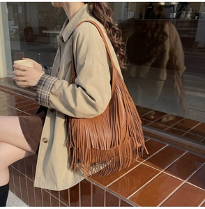Bohemian brown tassel bucket bag shown with a stylish trench coat in an outdoor setting