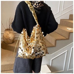 Detail view of large gold sequins on a hobo shoulder bag with a pleated satin strap