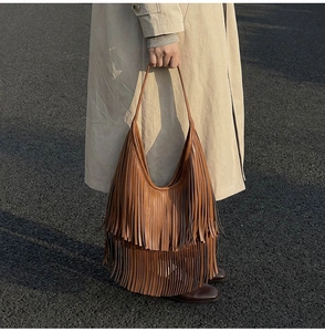 Close-up of brown fringe tote bag with tiered tassels and wide shoulder strap detail