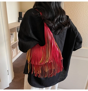 Detail view of large red tassel bucket bag with layered fringes shown on a model