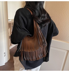 Brown tassel bucket bag with bohemian fringe detail shown worn by a model