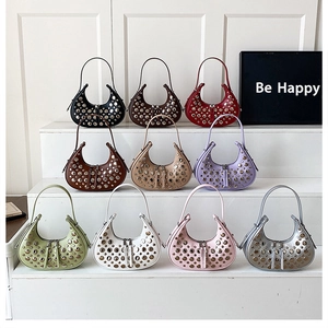 Collection of rivet studded crescent shoulder bags in multiple colors on a white display