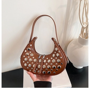Detail of a brown moon-shaped hobo bag with silver studs and smooth leather texture