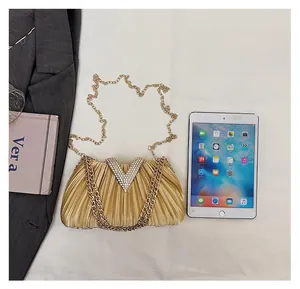 Comparaison de taille de la pochette dorée plissée avec strass V et un iPad Mini
