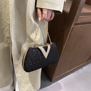 Elegant black evening clutch with V-shaped rhinestone buckle and gold chain strap