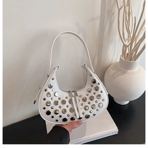 Close-up of stylish white crescent handbag with silver studs on a minimalist background