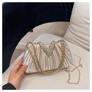 Gros plan d'un sac de soirée champagne avec tissu plissé et boucle V en strass
