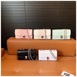 Detail showing various colors of glossy snakeskin pattern crossbody bags with silver chains