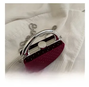 Détail du fermoir argenté et de la poignée sur le mini sac de soirée en velours bordeaux