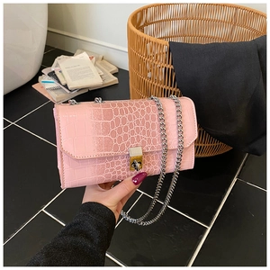 Detailed view of pink snakeskin textured small square bag with silver chain and metal buckle