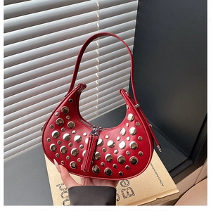 Detailed view of silver metal rivets on red leather crescent-shaped underarm bag