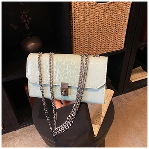 Detail of mint green crocodile embossed faux leather bag with silver chain strap