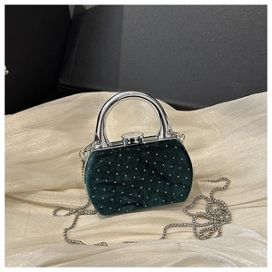 Détail du mini sac en velours vert foncé avec paillettes dorées et poignée en métal argenté