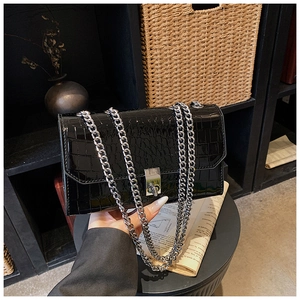 Detailed view of black crocodile pattern leather bag with silver metal chain strap