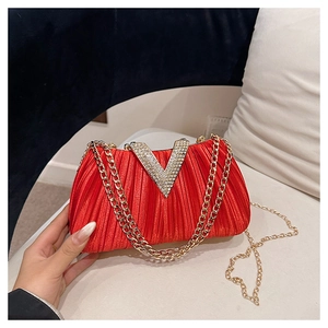 Détail de la pochette en satin plissé rouge avec boucle strass en V et bandoulière dorée