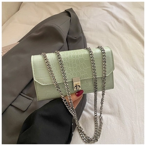 Detail of mint green faux crocodile leather bag with silver chain strap and metal clasp