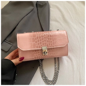 Close-up of pink faux leather bag with crocodile texture and silver chain strap