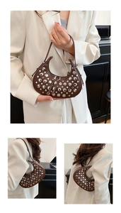 Detail of brown crescent bag with silver rivets and sleek zipper closure