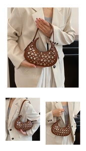 Detail view of dark brown crescent bag with silver rivets and long tassel zipper