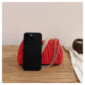 Détail de pochette de soirée plissée rouge avec boucle en strass et chaîne dorée