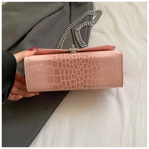 Close-up of pink faux leather bag with crocodile texture and silver chain strap