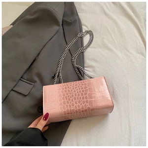 Detail of pink faux crocodile leather texture and silver chain strap on a stylish crossbody bag