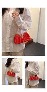 Détail du sac de soirée rouge plissé avec chaîne dorée et boucle en strass en V