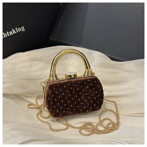 Détails d'un sac de soirée en velours marron avec clous dorés et poignée en métal chic