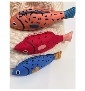 Detail of colorful fabric fish charms in orange red and blue on a woven tote bag